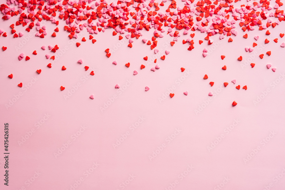 Red and pink small hearts decorations on pink background. Valentines Day frame border. Love, romance concept.