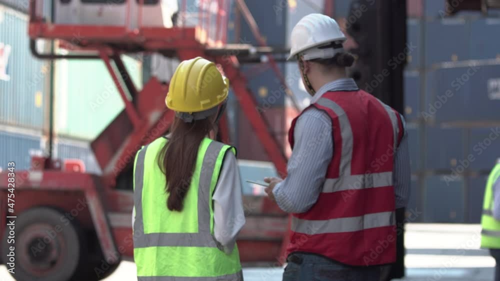 Engineer and foreman team in hardhat and safety vest control loading containers box from cargo, Logistic concepts. Engineer and foreman team in hardhat and safety vest control loading containers box from cargo, Logistic concepts.