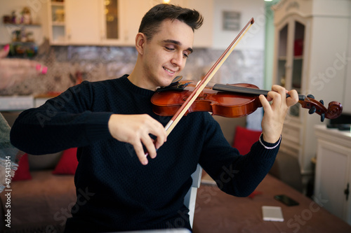 Cuadro en lienzo One young adult caucasian man sitting on the chair at home learning to play viol