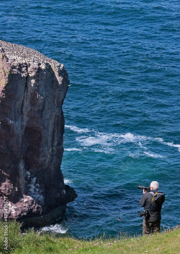 Tourist photographing rock in the ocean, St Abb's Head National Nature Reserve, Scotland, UK photo