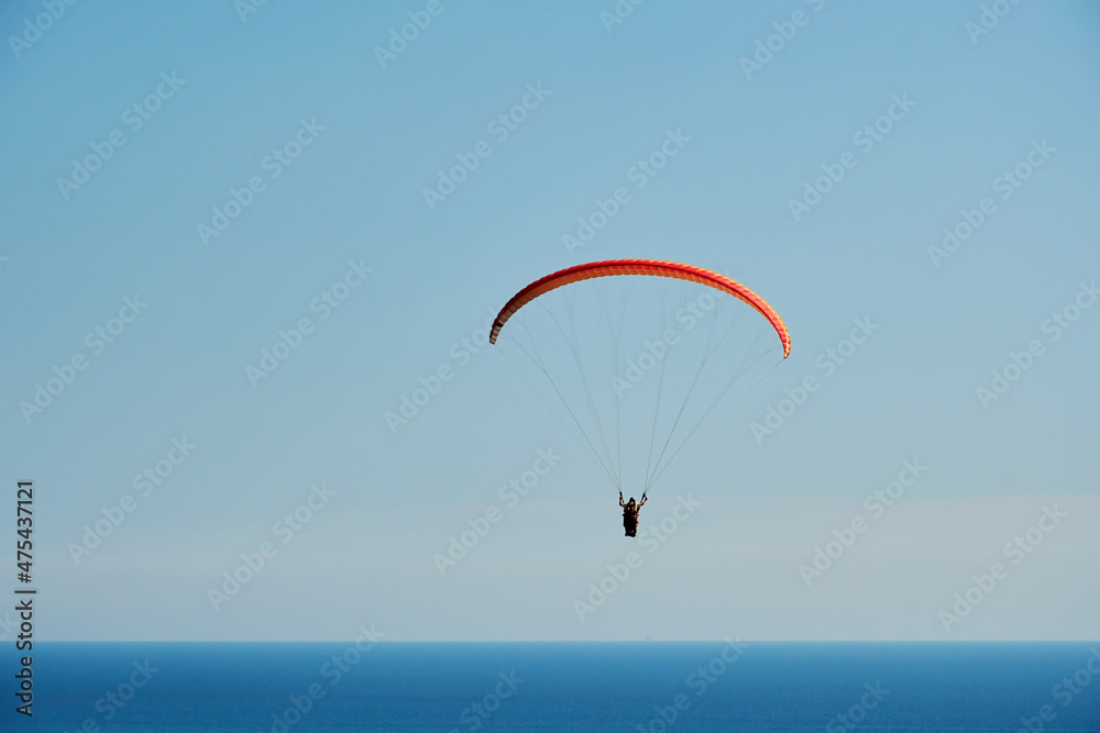 The paraglider hovers high in the sky above the blue sea. Extreme sport backgrounds The paraglider hovers high in the sky above the blue sea. Extreme sport backgrounds