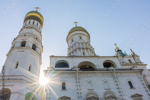 Ivan the Great Bell Tower, with Assumption Belfry on the right in Moscow Kremlin. Blue sky background with sunbeams