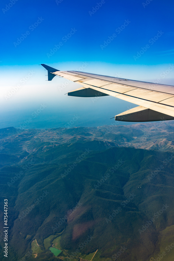 View from the airplane window at a beautiful blue clear sky and the airplane wing