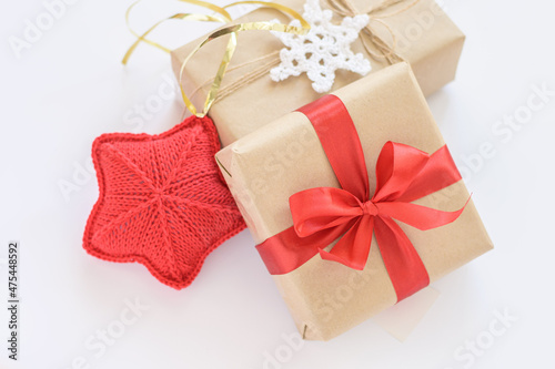 Christmas and New Years decorated gifts. Gift box wrapped in kraft paper with red ribbon. Red knitted heart. Box with jute cord and crocheted snowflake