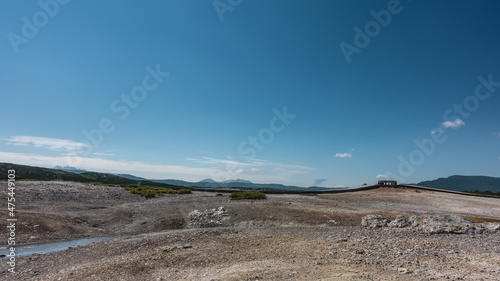 The rocky soil in the caldera of an extinct volcano is covered with sulfur deposits. Wooden paths for tourists are laid above the ground. Clear blue sky. Copy space. Kamchatka. Uzon