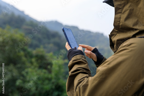Successful hiker using smartphone on mountain top
