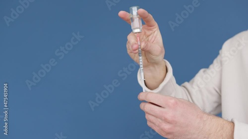 filling insulin syringe from vial with blue background space for text photo