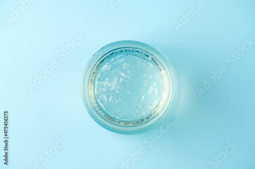 Jar of transparent cosmetic gel on blue background. Top view