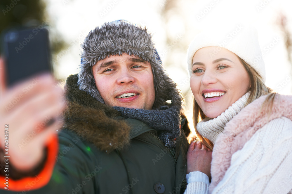 Young couple having fun on snow taking selfie
