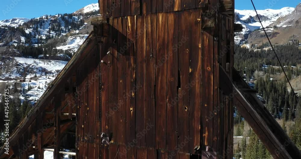 Abandoned antique mining structure in Colorado mountains with drone shot moving up.