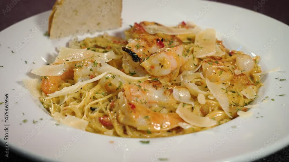 Shrimp over angel hair pasta with focaccia bread and shaved parmesan sprinkled with herbs in white dish, slider 4K Shrimp over angel hair pasta with focaccia bread and shaved parmesan sprinkled with herbs in white dish, slider 4K