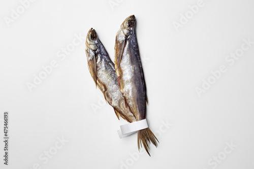 Two jerked or dried salted sabrefish with paper labels on tails isolated on white photo