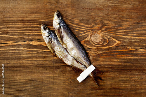 Two salted air-dried sabrefish with paper labels on tails on wooden background photo