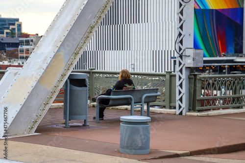 a young man sitting on a bench on the John Seigenthaler Pedestrian Bridge in Nashville Tennessee USA photo