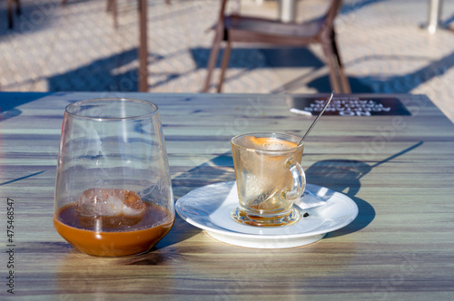 A GLASS WITH ICE AND COFFEE WITH MILK ON TOP OF A TABLE ON A TERRACE, ALICANTE, SPAIN © Pepeelson