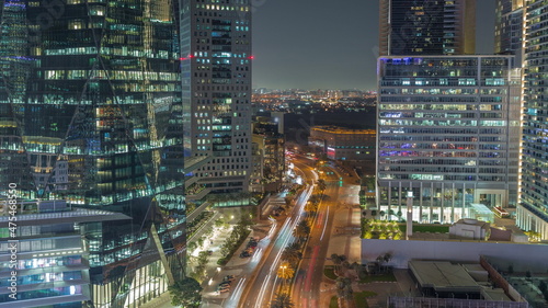 Traffic on a road in Dubai International Financial district aerial night timelapse. Panoramic view of business and financial office towers.