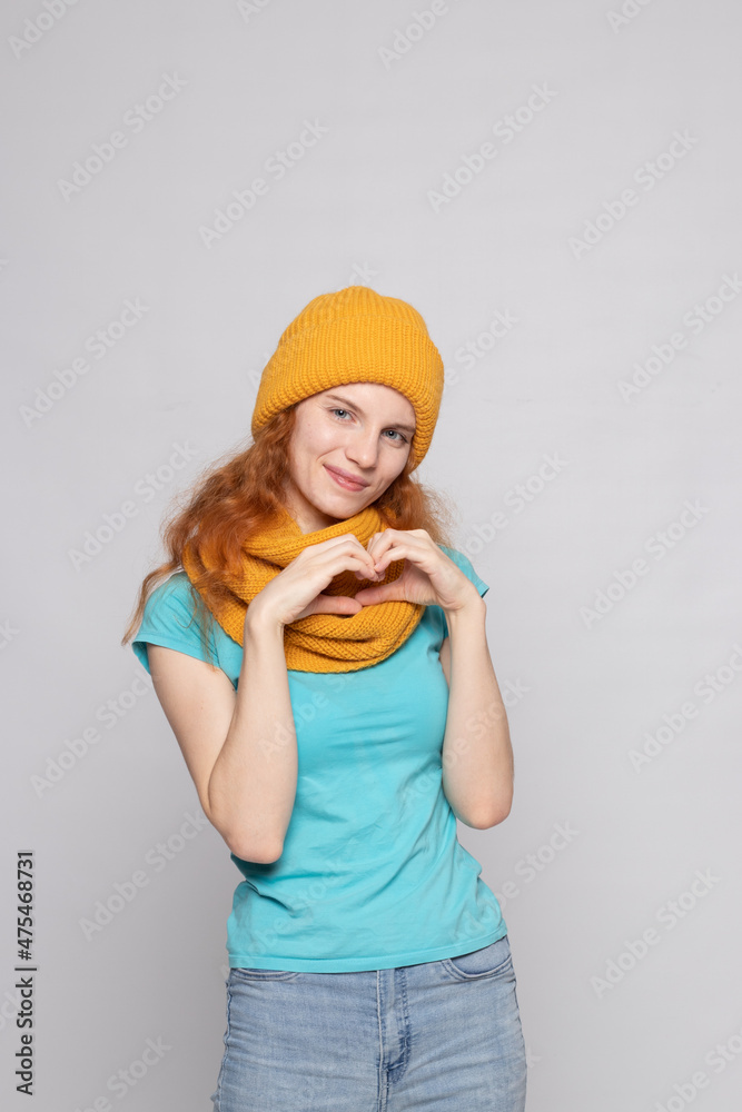red-haired girl in a warm hat on a light background red-haired girl in a warm hat on a light background