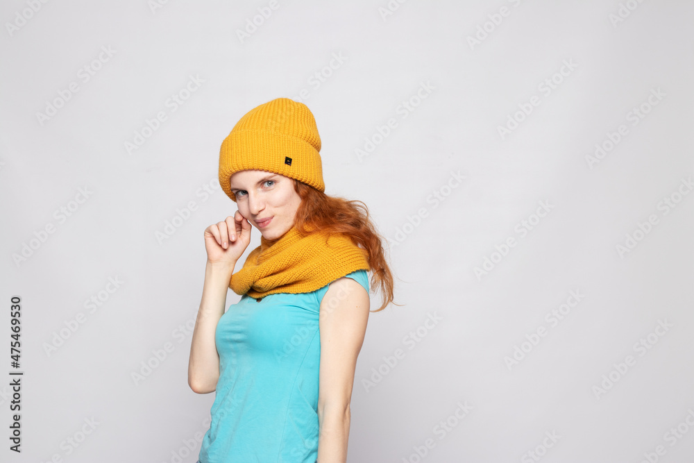 red-haired girl in a warm hat on a light background red-haired girl in a warm hat on a light background