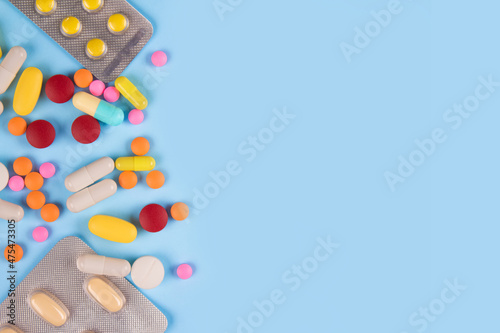 Assorted multicolored medicine pills, capsules and tablets on blue background with copy space. Immune system vitamins and supplemets. Dietary bio supplements photo