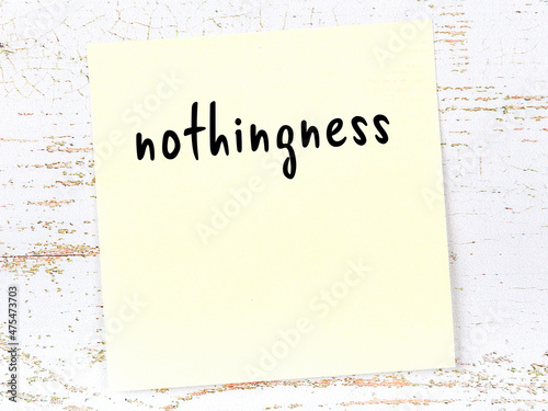 Yellow sticky note on wooden wall with handwritten word nothingness photo