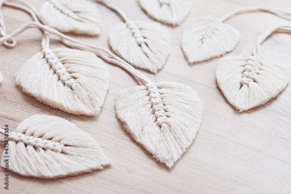 Macrame leaves in natural color on the wooden background. Cotton rope decor macrame to make your home more cozy and unique. Woman hobby. Macrame leaves in natural color on the wooden background. Cotton rope decor macrame to make your home more cozy and unique. Woman hobby.