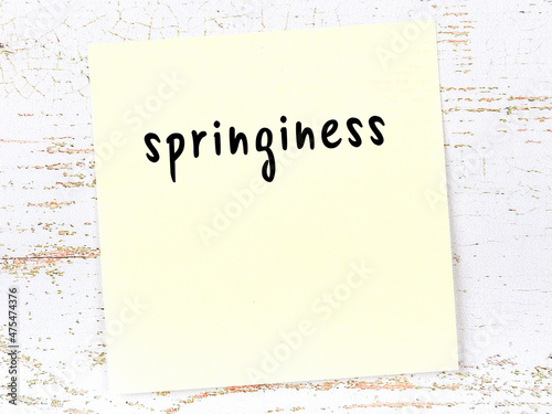 Yellow sticky note on wooden wall with handwritten word springiness photo