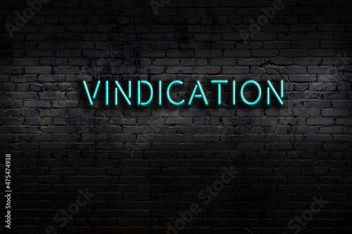 Night view of neon sign on brick wall with inscription vindication photo