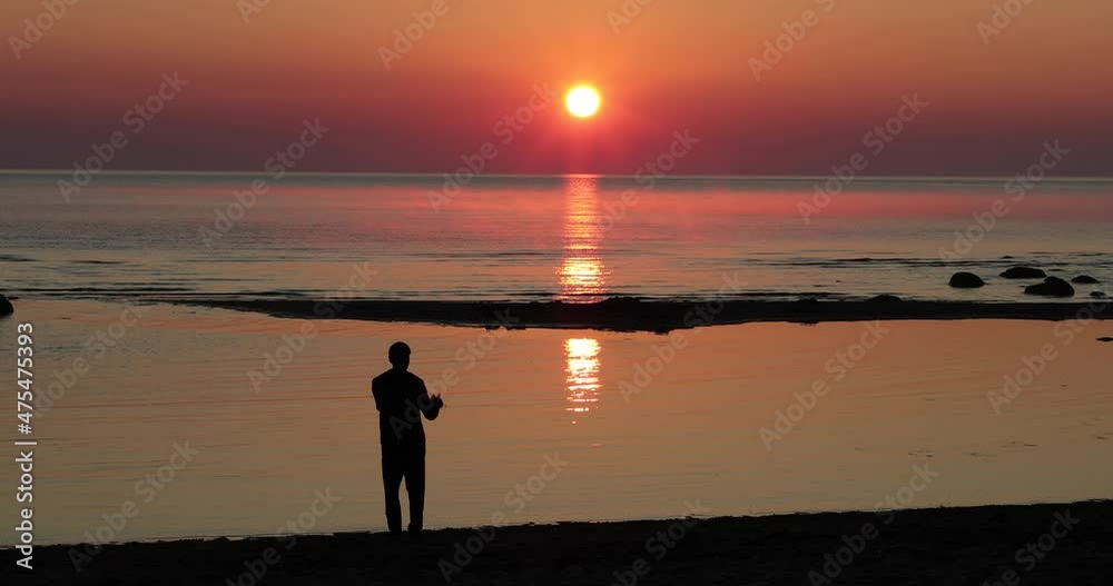 guy with a video camera shoots the dawn on a sandy beach near the sea guy with a video camera shoots the dawn on a sandy beach near the sea