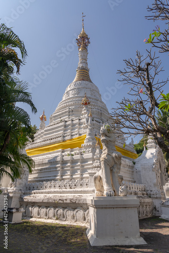 Scenic low angle view of beautiful ancient burmese style white stupa or chedi with guardian lion at Wat Mahawan buddhist temple, Chiang Mai, Thailand
