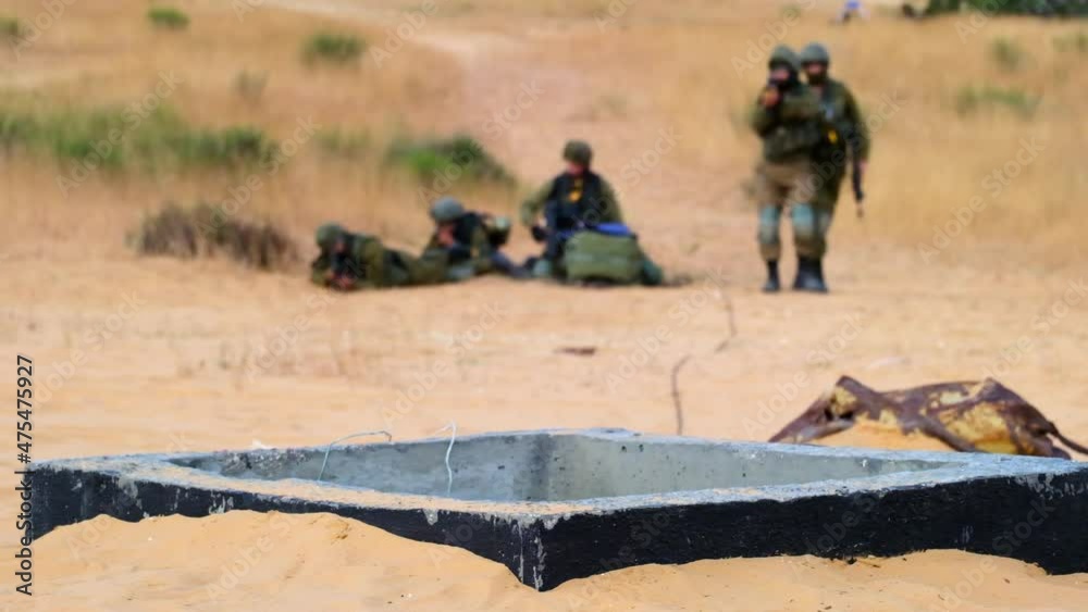 Two soldiers walk towards the opening of a tunnel while their friends cover for them in the background Two soldiers walk towards the opening of a tunnel while their friends cover for them in the background