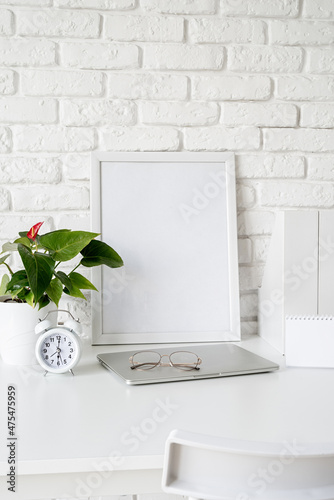 Front view of desk arrangement with blank calendar for mock up, paper folders and white frame with copy space