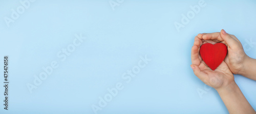 a small heart in children's hands on a blue background, a banner with a place for text