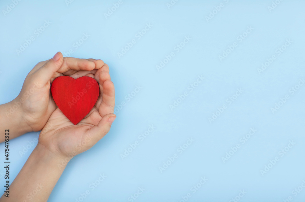 a small heart in children's hands on a blue background a small heart in children's hands on a blue background