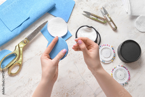 Woman with needle and fabric for reusable cotton pad on light background