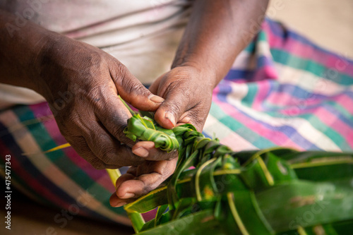 Woman weaving a coconut palm leaf into a basket for market shopping in the Solomon Islands. photo