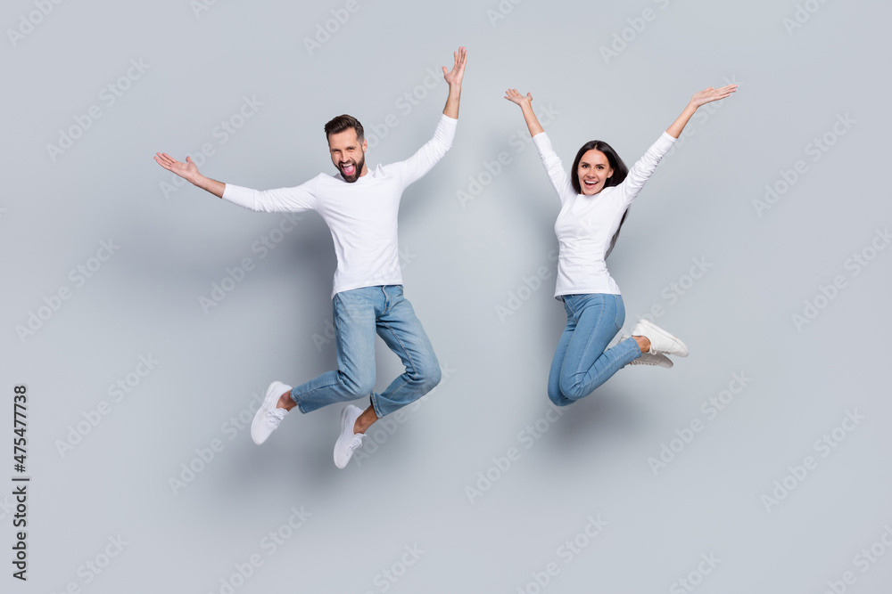 Full size photo of nice young brunet couple jump wear white shirt jeans footwear isolated on grey background