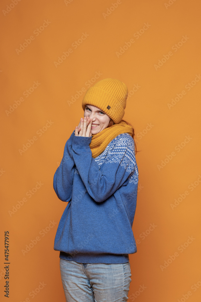 young red-haired girl in a warm hat and a knitted sweater on a yellow background young red-haired girl in a warm hat and a knitted sweater on a yellow background