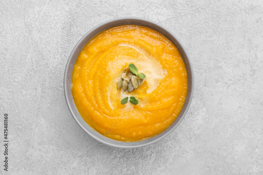 Bowl of tasty pumpkin cream soup on grey background Bowl of tasty pumpkin cream soup on grey background