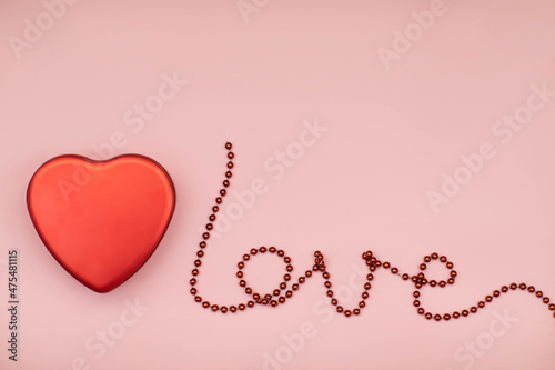 the word love of red beads on a pink background red heart, a day of lovers