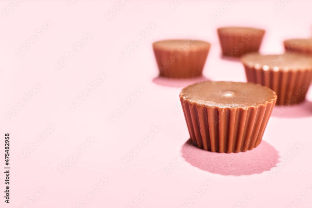 Tasty peanut butter cups on color background