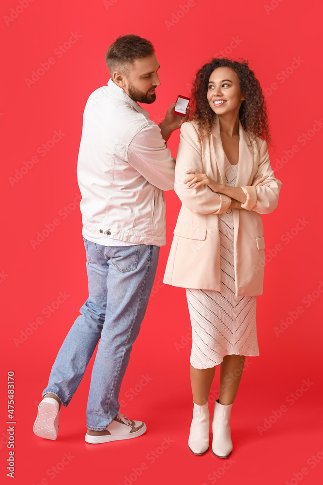 Young man proposing to his girlfriend on color background Young man proposing to his girlfriend on color background