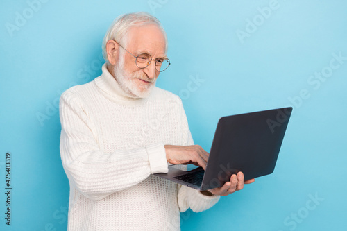 Photo of nice aged beard man look laptop wear eyewear white turtleneck isolated on blue color background