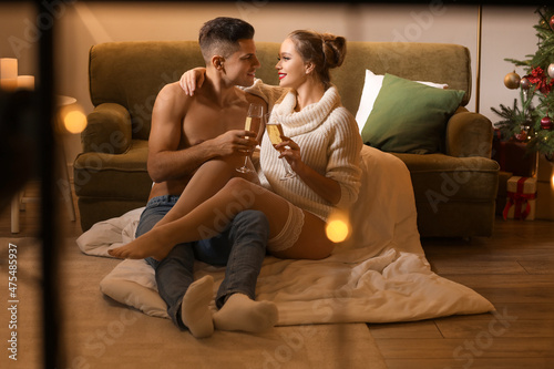 Sexy young couple drinking champagne while having romantic date on Christmas eve