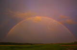 Lightning with with beautiful rainbow, fresh rain in the summer field landscape