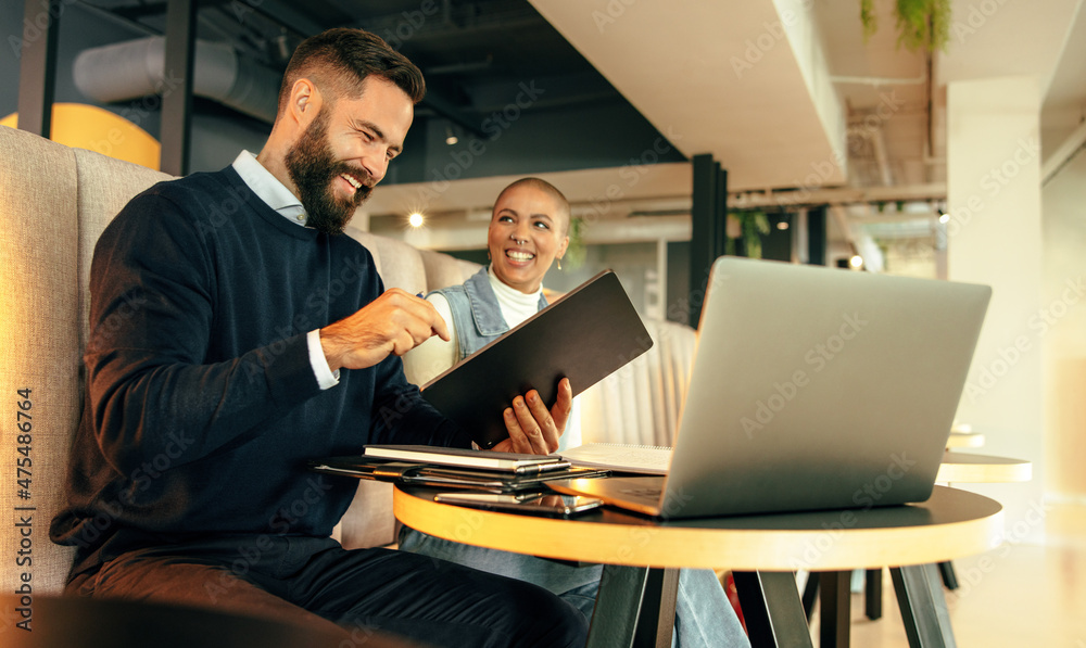 Two happy businesspeople working together in a co-working space Two happy businesspeople working together in a co-working space