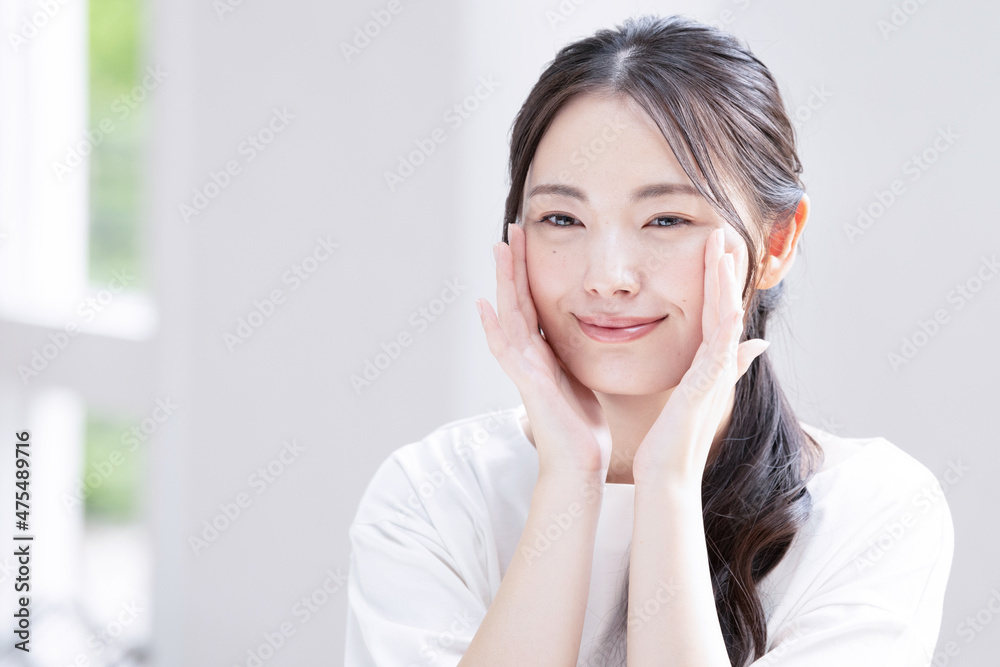 Beautiful young Asian (Japanese) woman smiling with concern for her skin condition Close-up Copy space available Beautiful young Asian (Japanese) woman smiling with concern for her skin condition Close-up Copy space available