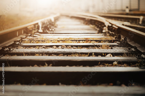 Empty old railway rails with wooden sleepers, illuminated by sunlight. The road for the train. Journey.