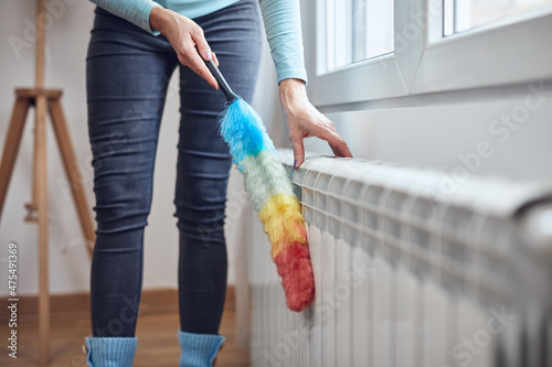 Bild auf Leinwand Woman with a dust stick cleaning central heating gas radiator at home