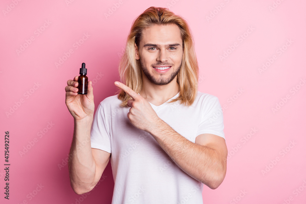 Photo of cheerful young positive man point finger essential oil promo isolated on pink color background Photo of cheerful young positive man point finger essential oil promo isolated on pink color background