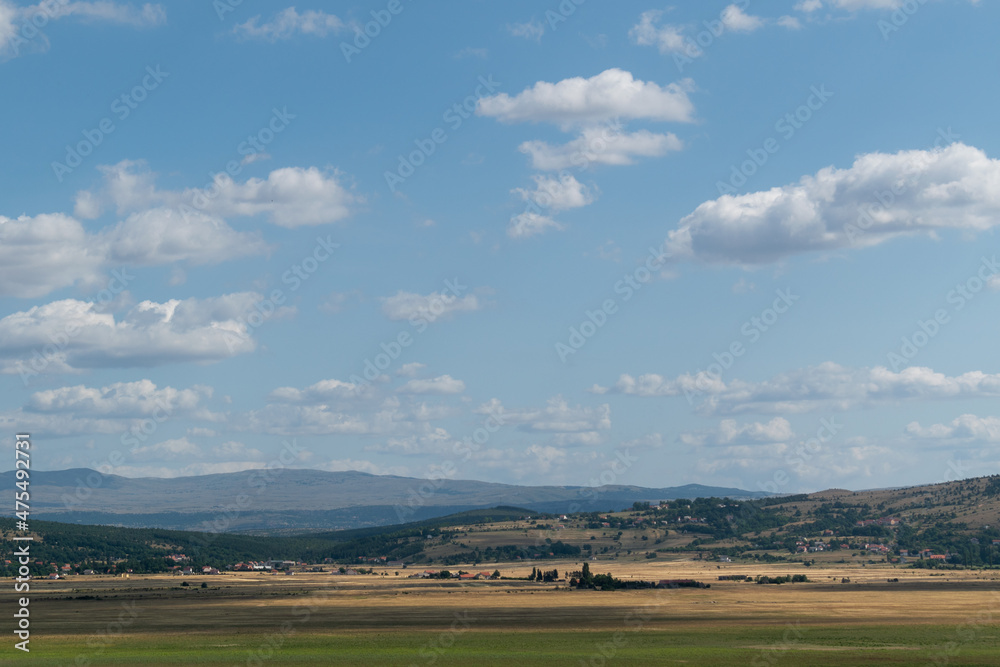 Landscape of rural settlement and mountains in the background near Livno, Bosnia and Herzegovina during a sunny summer day